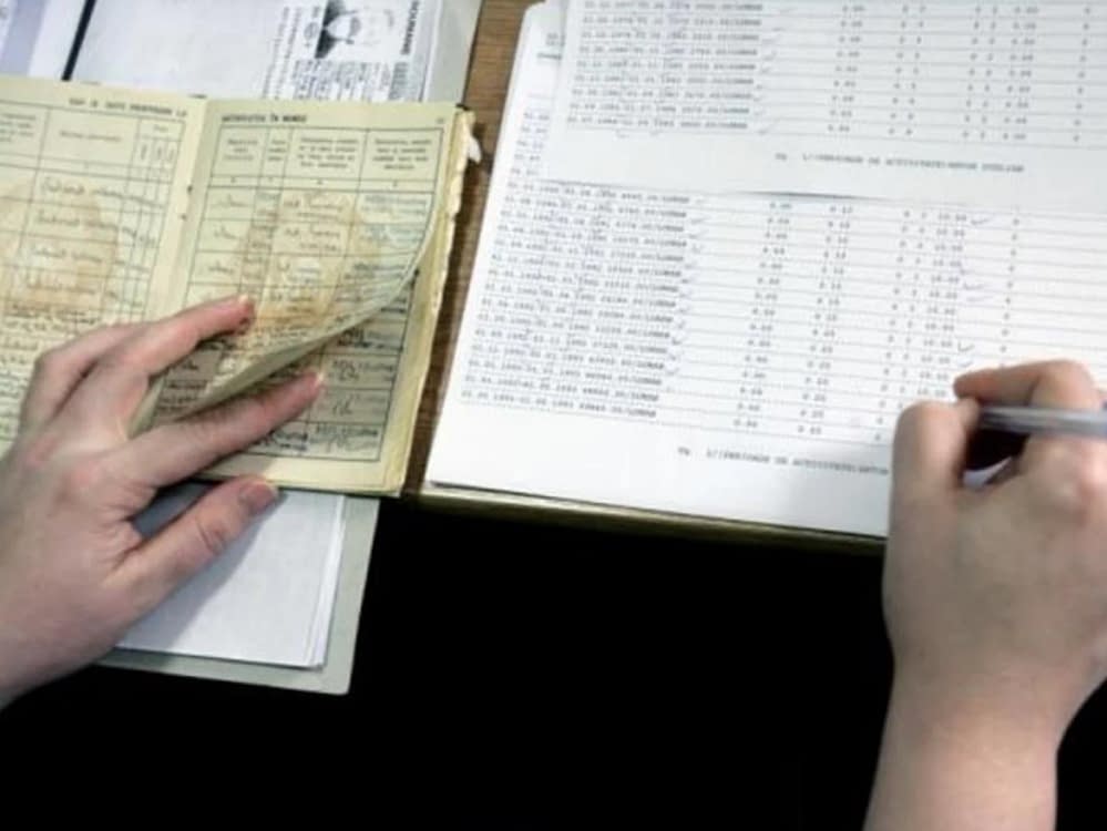 Cineva transcrie date din cartea de muncă într-un registru