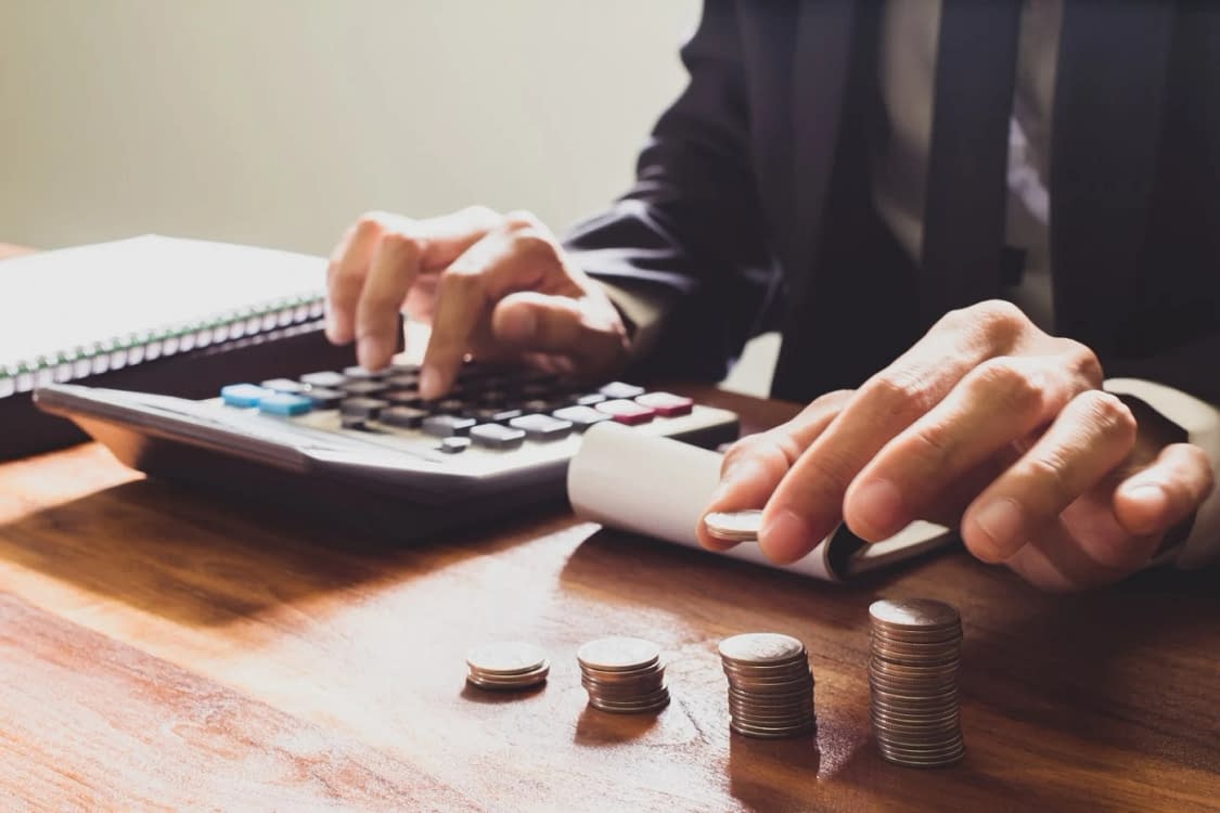 Cineva face calcule la un calculator în timp ce pune monede deoparte
