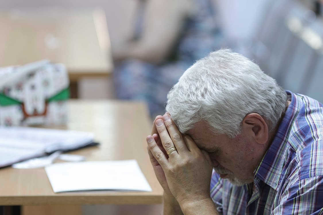Un pensionar stă cu capul sprijinit în mâini
