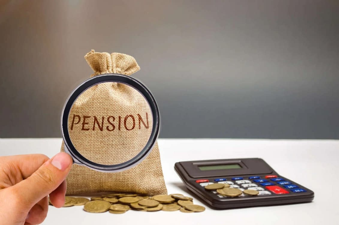 Lupa pusă pe un săculeţ pe care scrie Pension lângă un calculator şi câteva monede